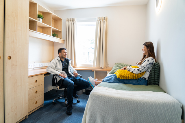 Two students sat talking in bedroom