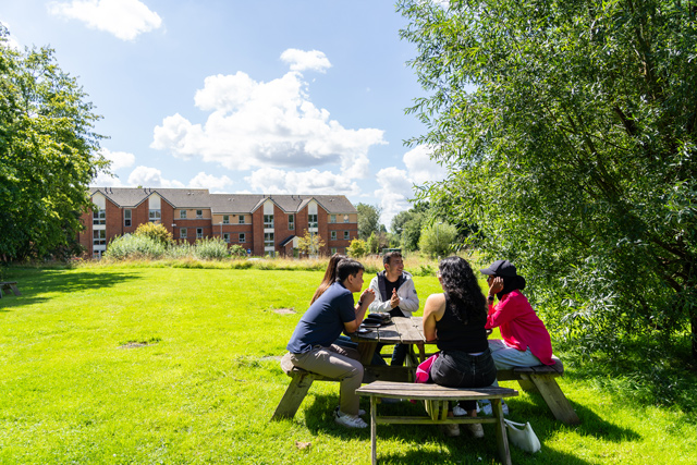 Students sat on bench outside Benyon Halls